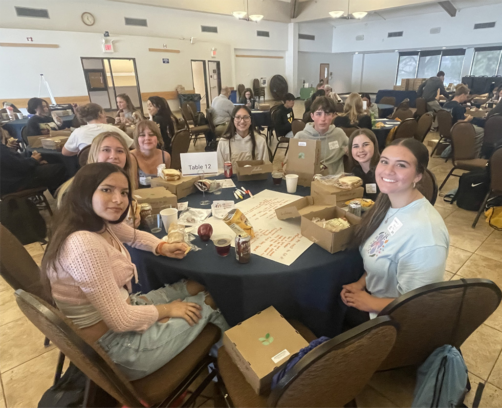 Room full of happy young adults sitting at round tables