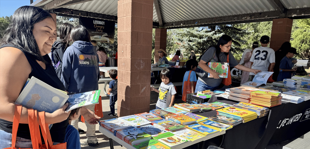 Summer Literacy Fair with parents and children looking through tables filled with books