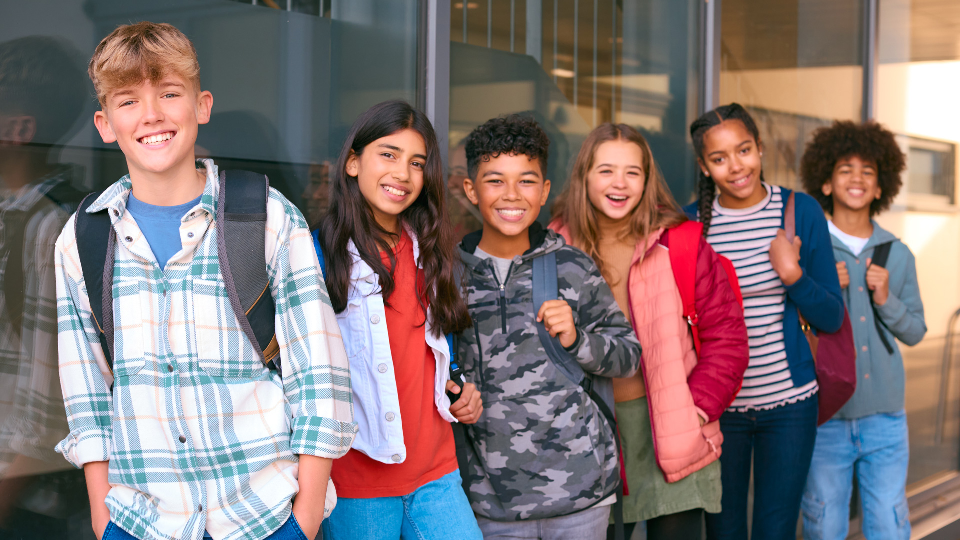 Photo of six young teens standing next to each other, all smiling