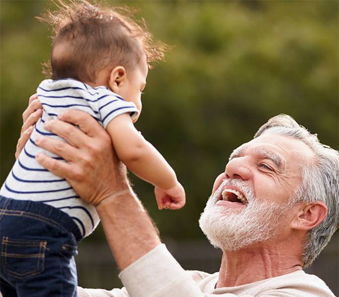 Grandparent lifting a baby up and interacting with them